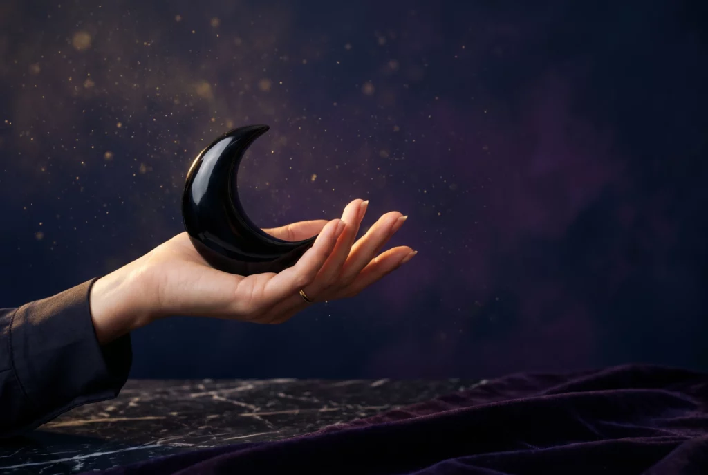 Lilith astrologie — main tenant un croissant en obsidienne noire sur fond cosmique violet